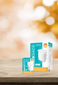 The Rack Sack 5 Gallon Trash Bin and 48 Count Bag Refills on wooden surface, compact in-cupboard waste system for efficient kitchen tidiness and organization.